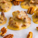 Southern pecan pralines on parchment paper with pecans around them.