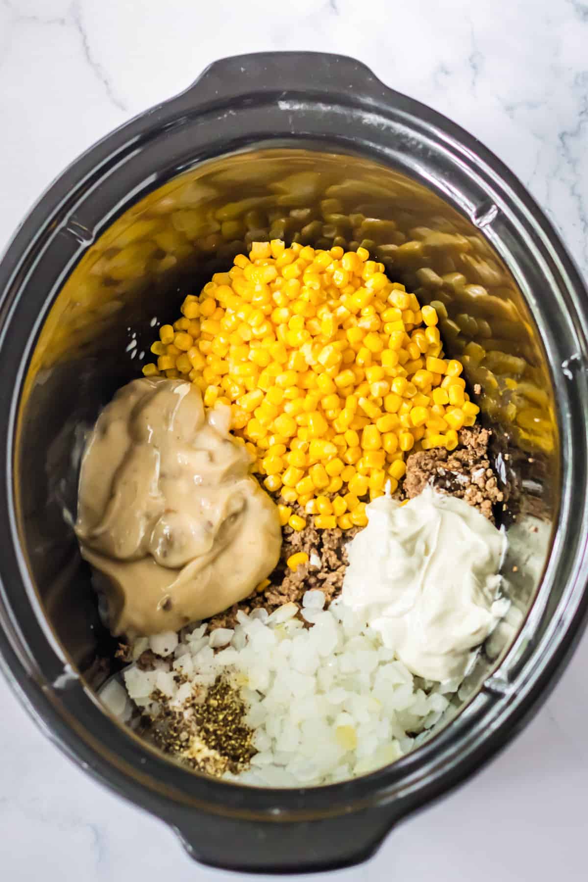 Ground beef, corn, soup, onion, seasonings, milk, and sour cream added to crockpot.