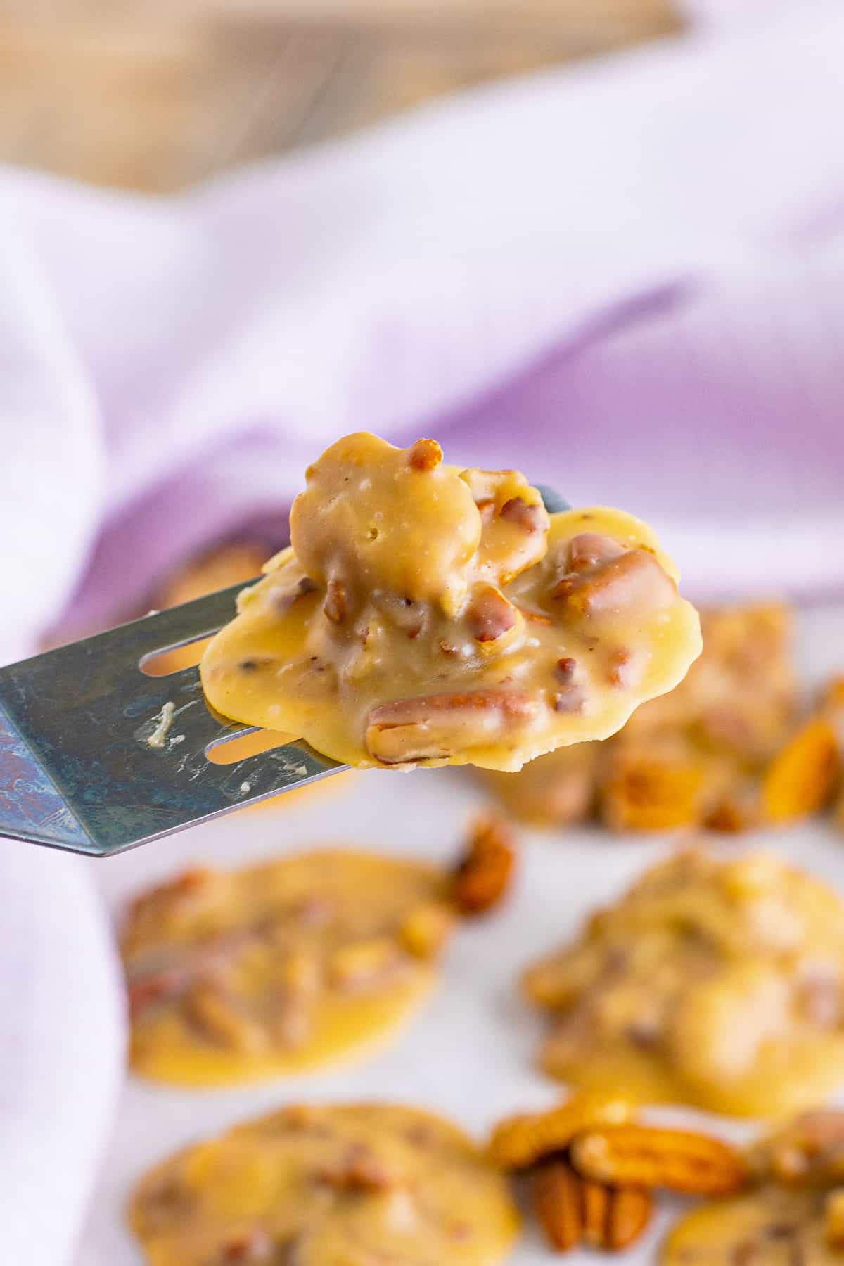 Spatula transferring a pecan praline candy after it has set.