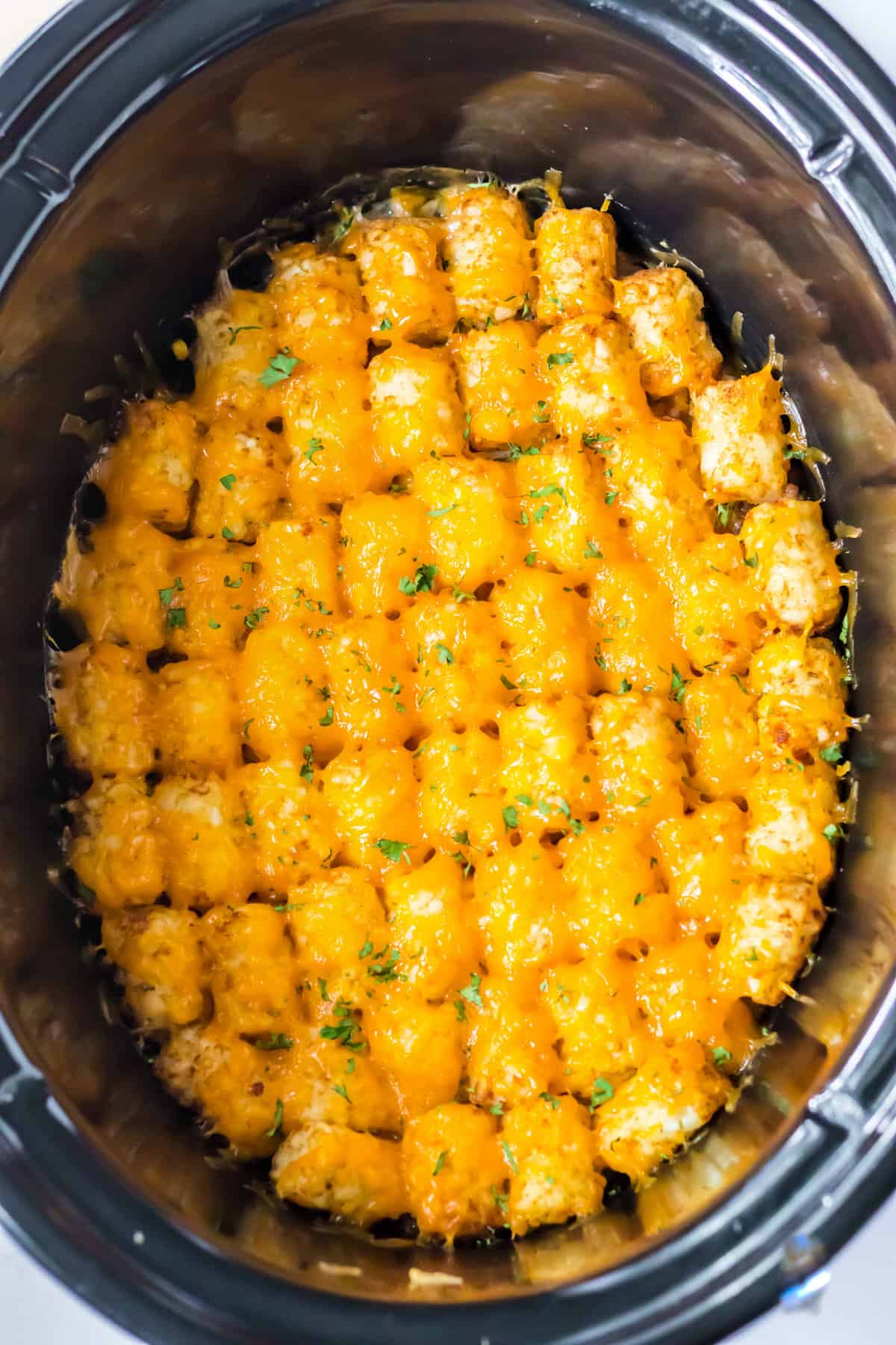 Slow cooker tater tot casserole topped with melted cheese.