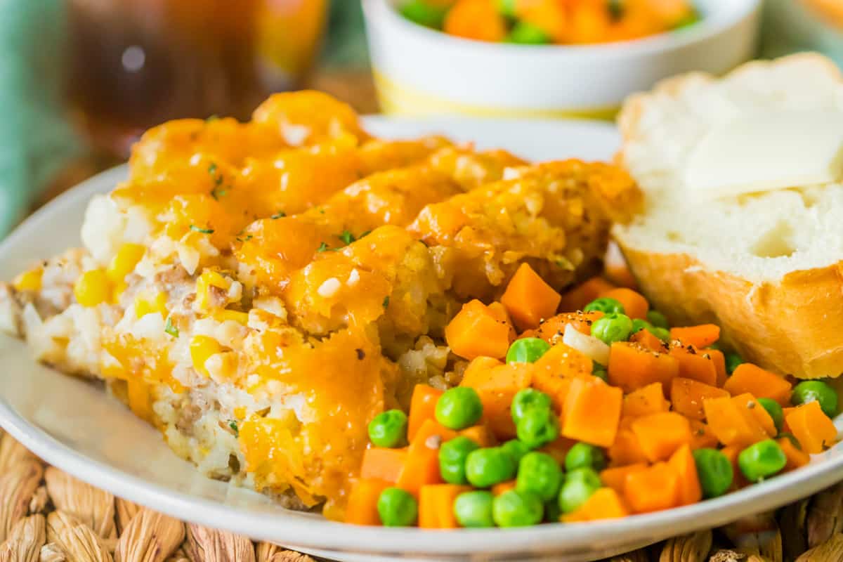 Plated portion of crock pot tater tot hot dish with veggies and buttered bread.