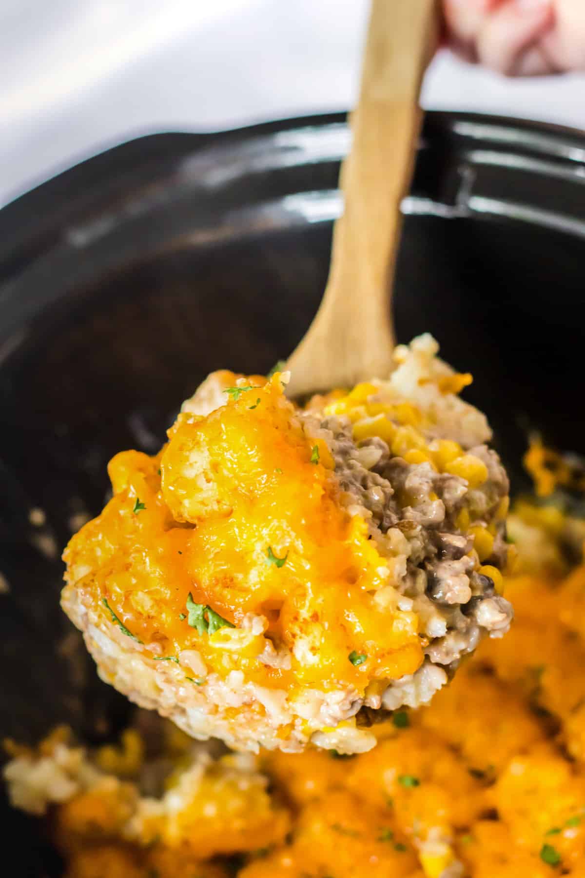 Spoon scooping out serving of slow cooker tater tot casserole.