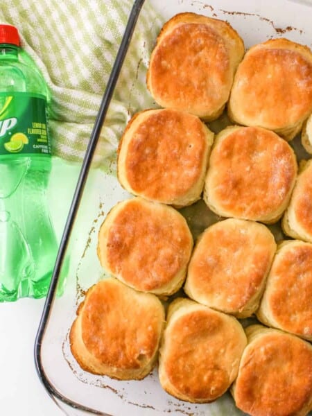 Golden brown 7 Up biscuits in rectangular pan with bottle of 7 up beside it.