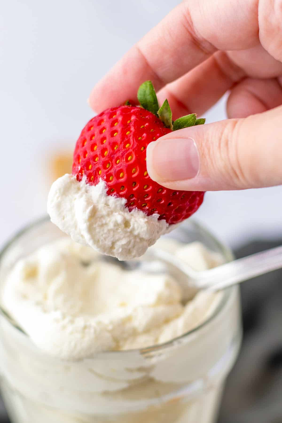 Light and fluffy homemade cool whip whipped topping on a fresh strawbery.
