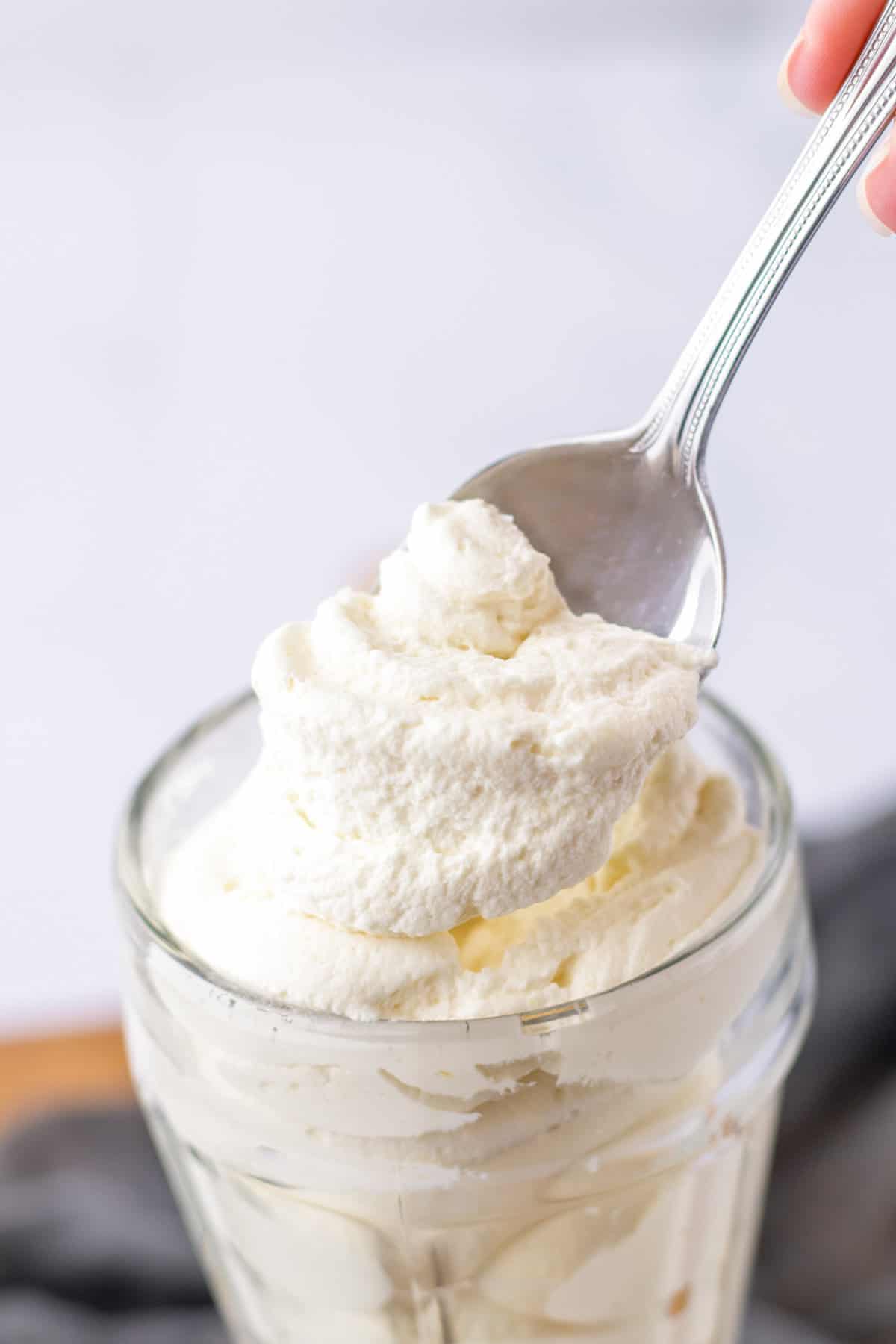 Homemade whipped topping being spooned out of glass. 