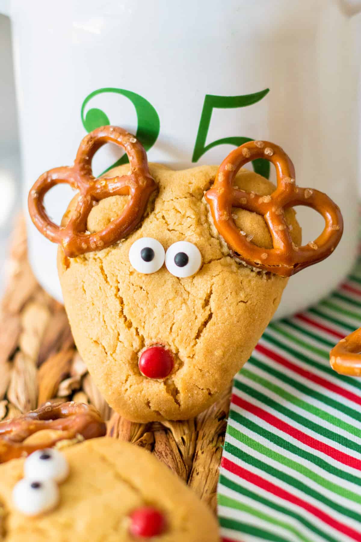 Peanut butter reindeer cookie with pretzel antlers, red M&M nose, and candy eyeballs.