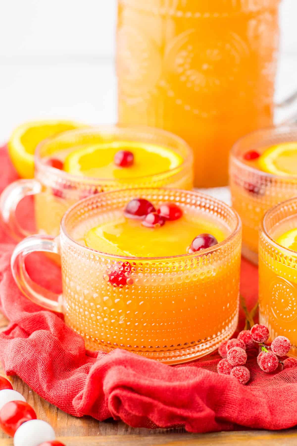Glasses of christmas morning punch with orange juice, pineapple juice, cranberry juice, ginger ale, and fresh cranberries and orange slices for garnish. 
