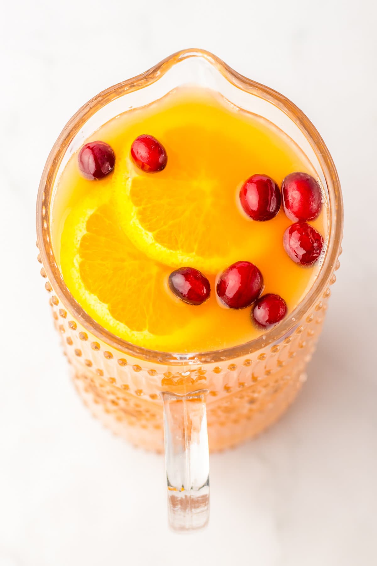 Pitcher of non alcoholic punch with cranberries and orange slices.