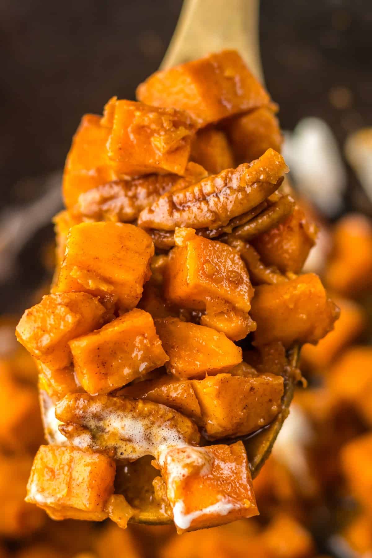 Wooden spoon scooping a serving of the sweet potato side dish out of the slow cooker.