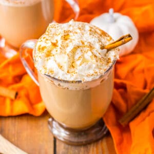 Crockpot Pumpkin Spice Latte in a glass mug topped with whipped cream, cinnamon, and a cinnamon stick.