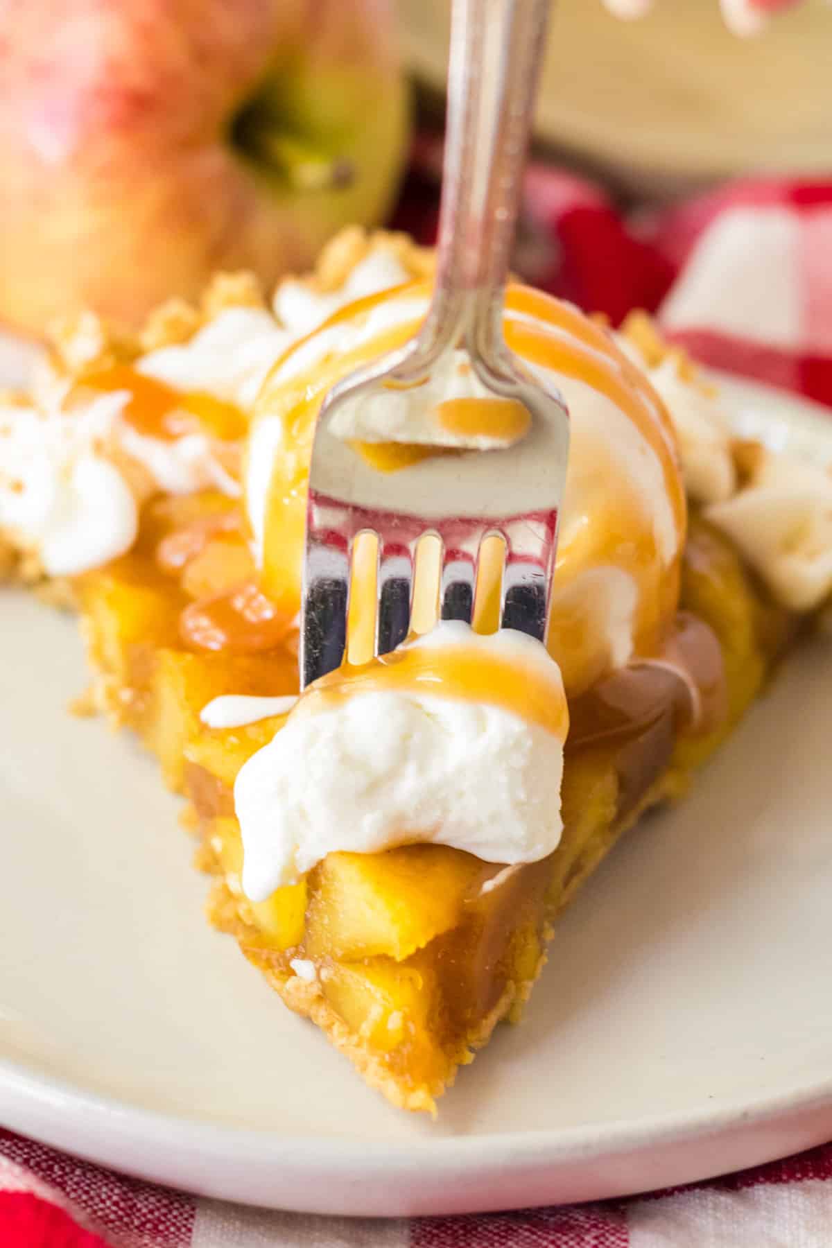 Fork going into a slice of no bake apple pie topped with ice cream and caramel.