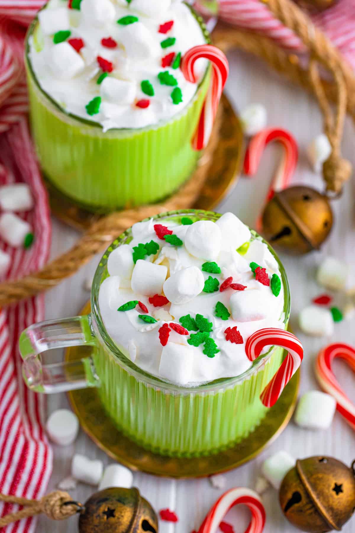 Green Christmas hot chocolate topped with whipped cream, mini marshmallows, and holiday sprinkles.