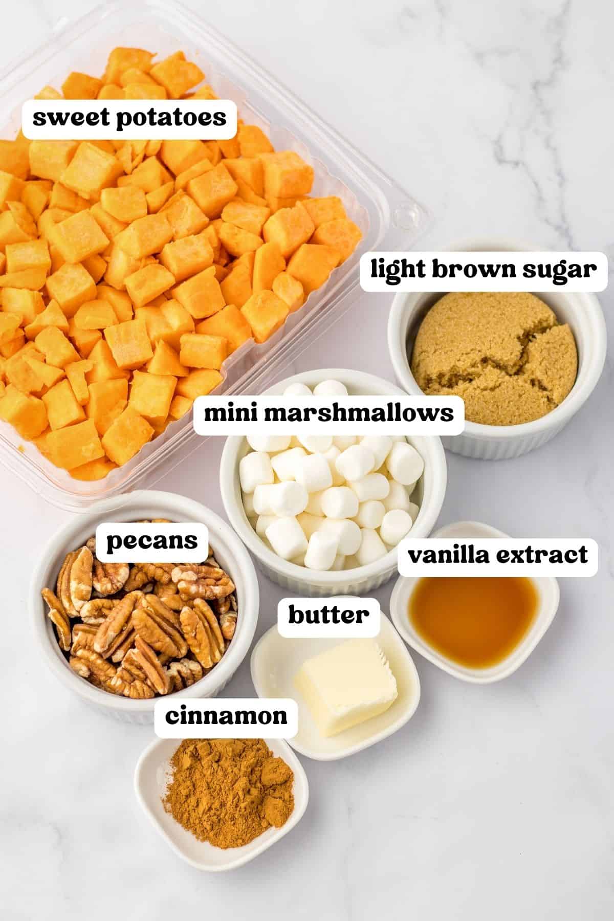 Ingredients on countertop: diced sweet potatoes, light brown sugar, vanilla extract, mini marshmallows, pecans, butter and cinnamon.