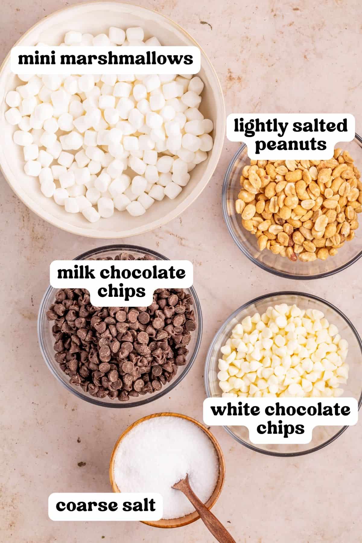 Mini marshmallows, lightly salted peanuts, milk chocolate chips, white chocolate chips, and coarse salt in bowls.