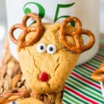 Peanut butter reindeer cookie with pretzel antlers, red M&M nose, and candy eyeballs.