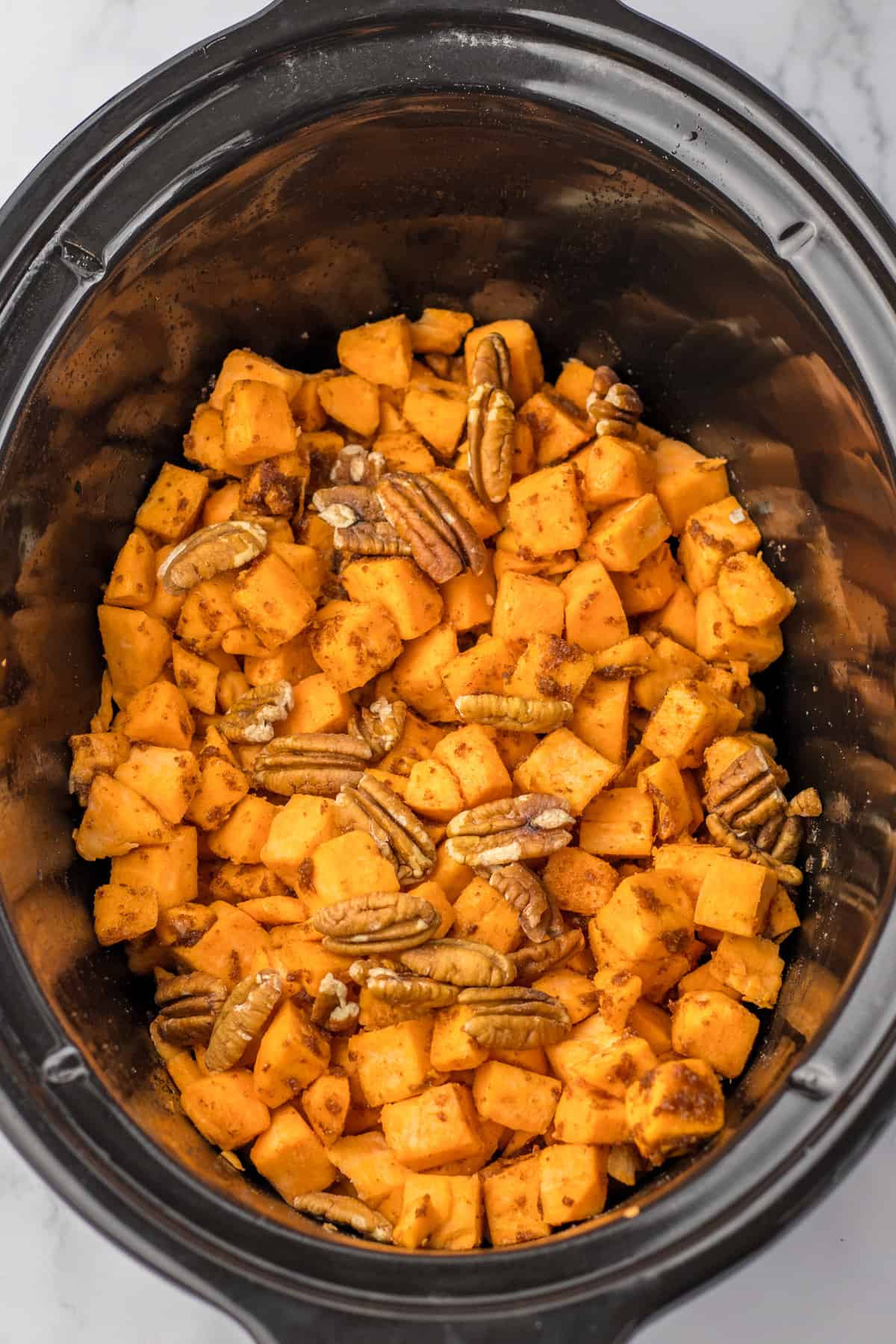 Diced sweet potatoes and pecans in a slow cooker.