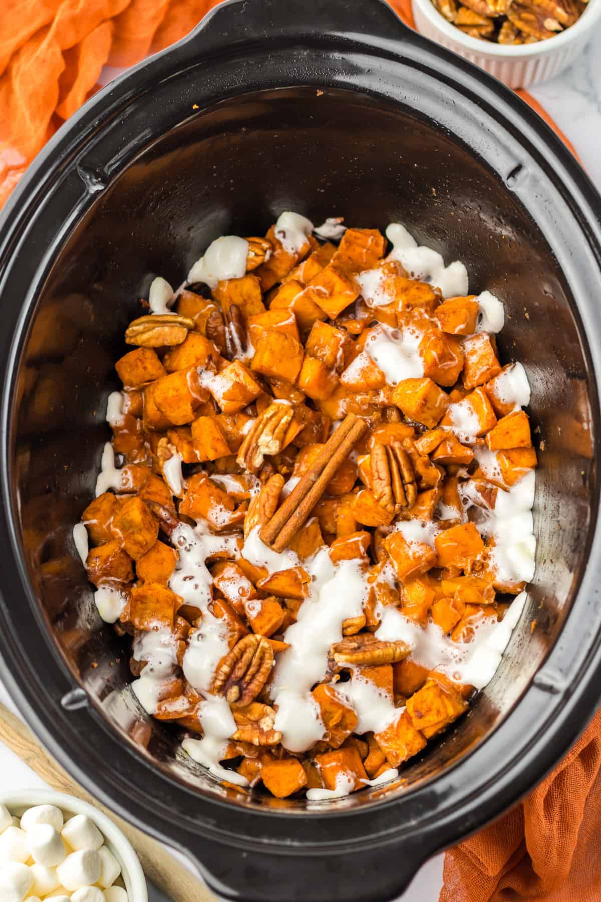Sweet potato casserole with pecans and marshmallows in a crockpot.
