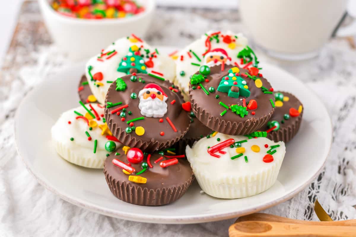 Homemade Christmas peanut butter cups topped with sprinkles and served on a white plate.