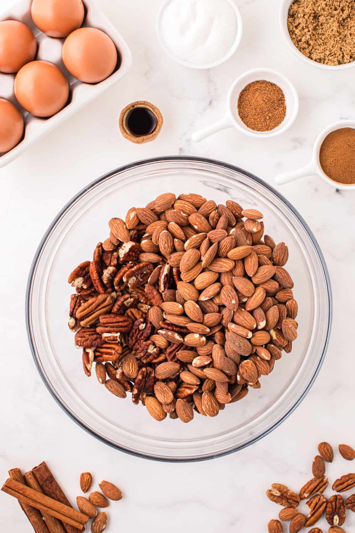 Raw almonds and pecan halves in a glass mixing bowl.