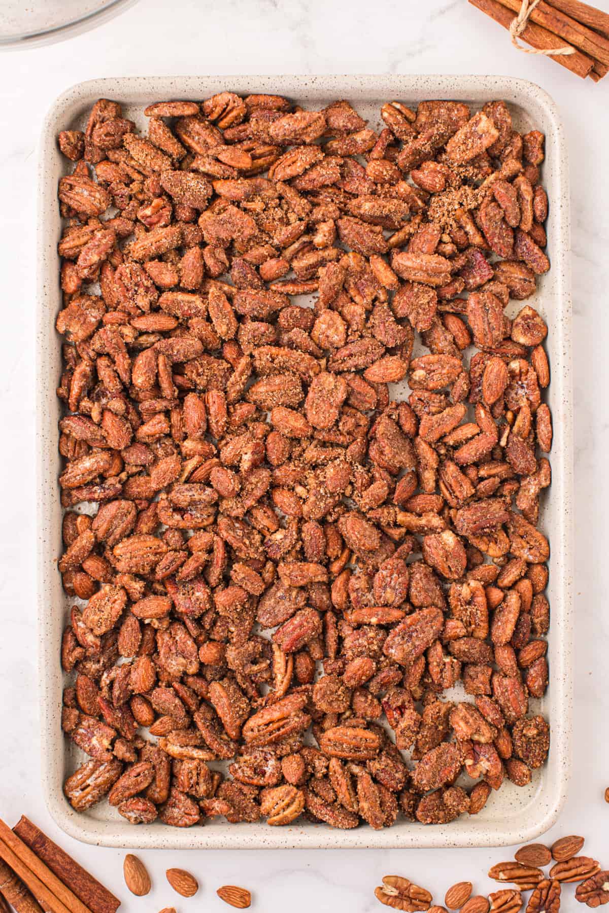 Coated nuts spread in an even layer on baking sheet.