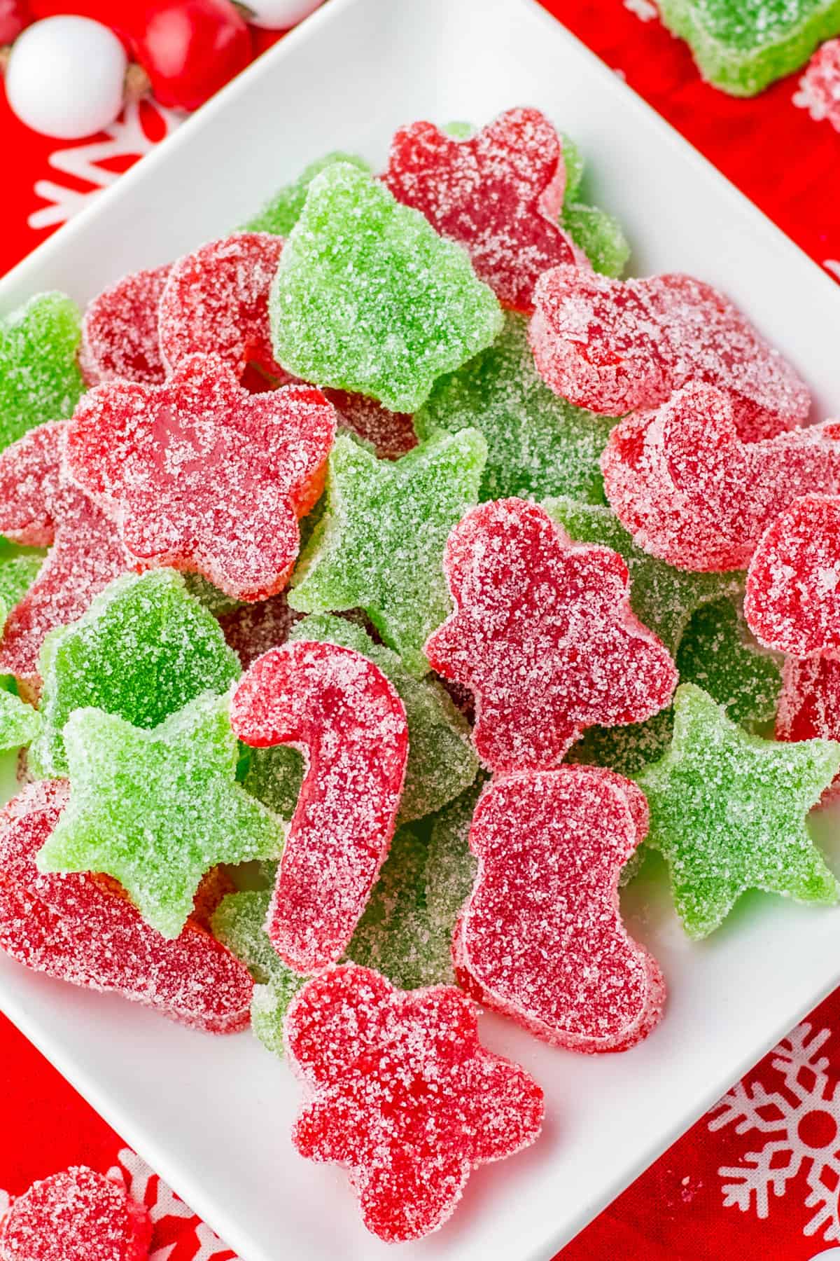 Red and green Christmas gumdrops cut into festive shapes piled on a white plate.