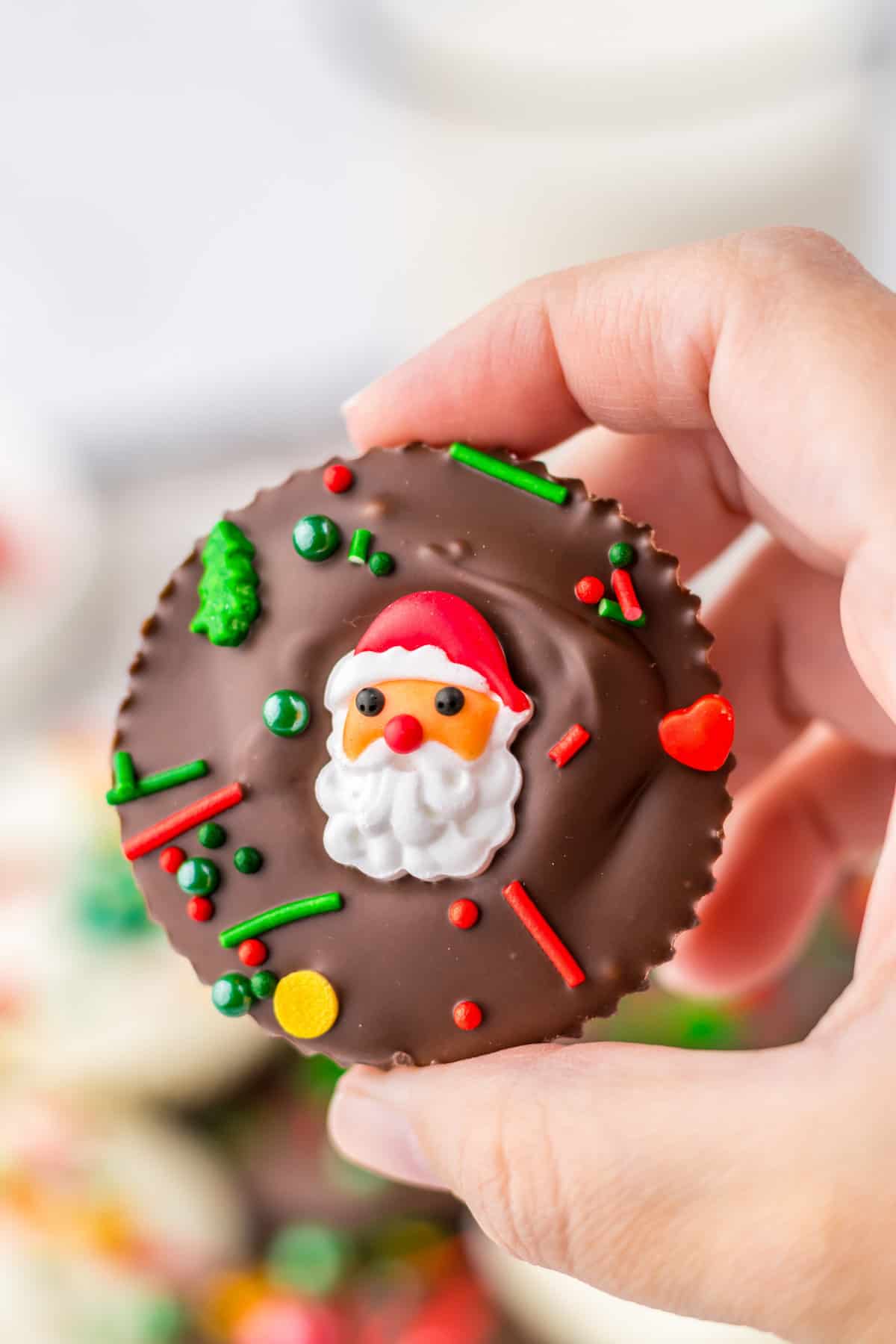 Hand holding homemade Reese's peanut butter cup with christmas sprinkles.