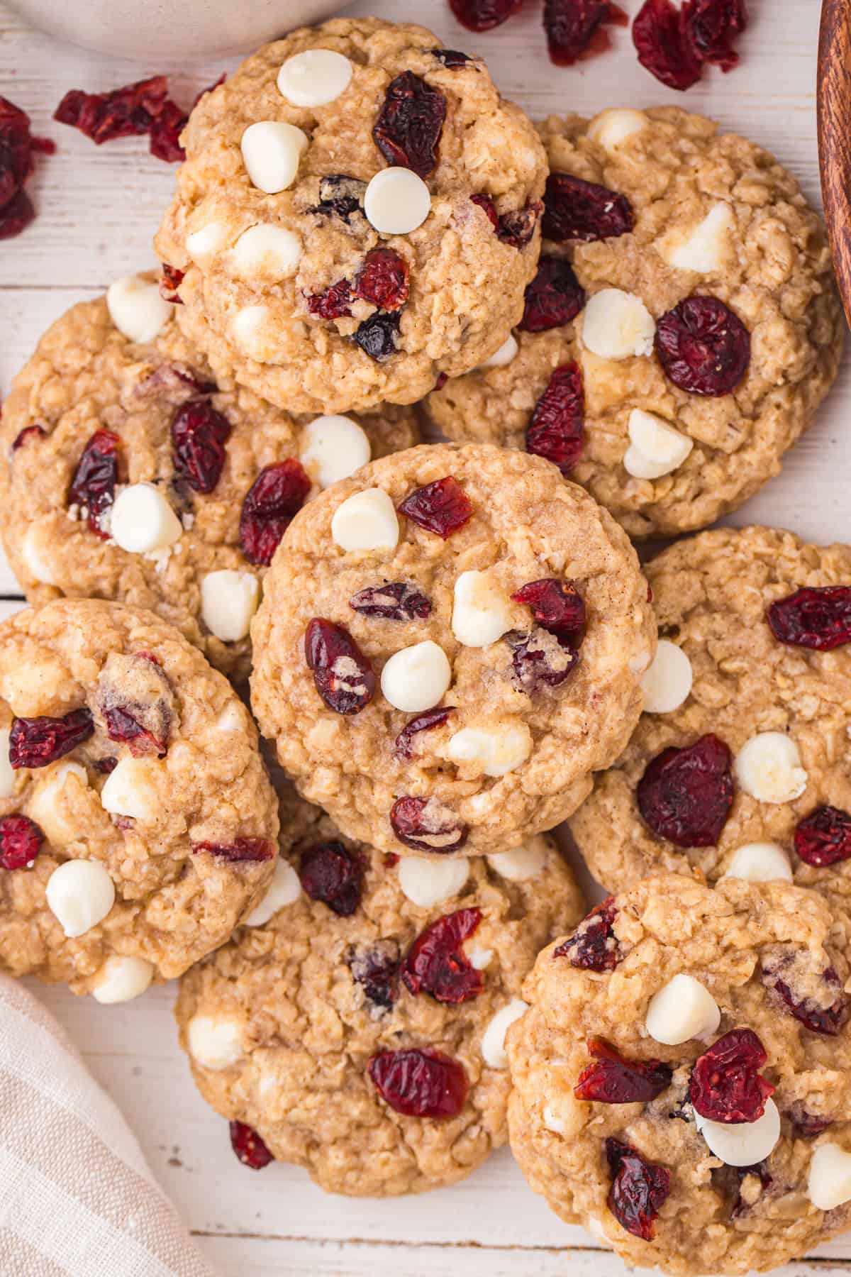 Cranberry oatmeal cookies with white chocolate chips scatted on a tabletop.