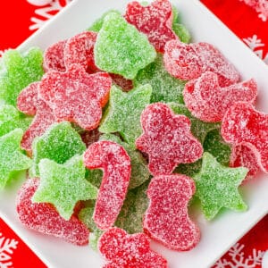Homemade red and green Christmas gumdrops cut into christmas shapes and piled on a white plate.