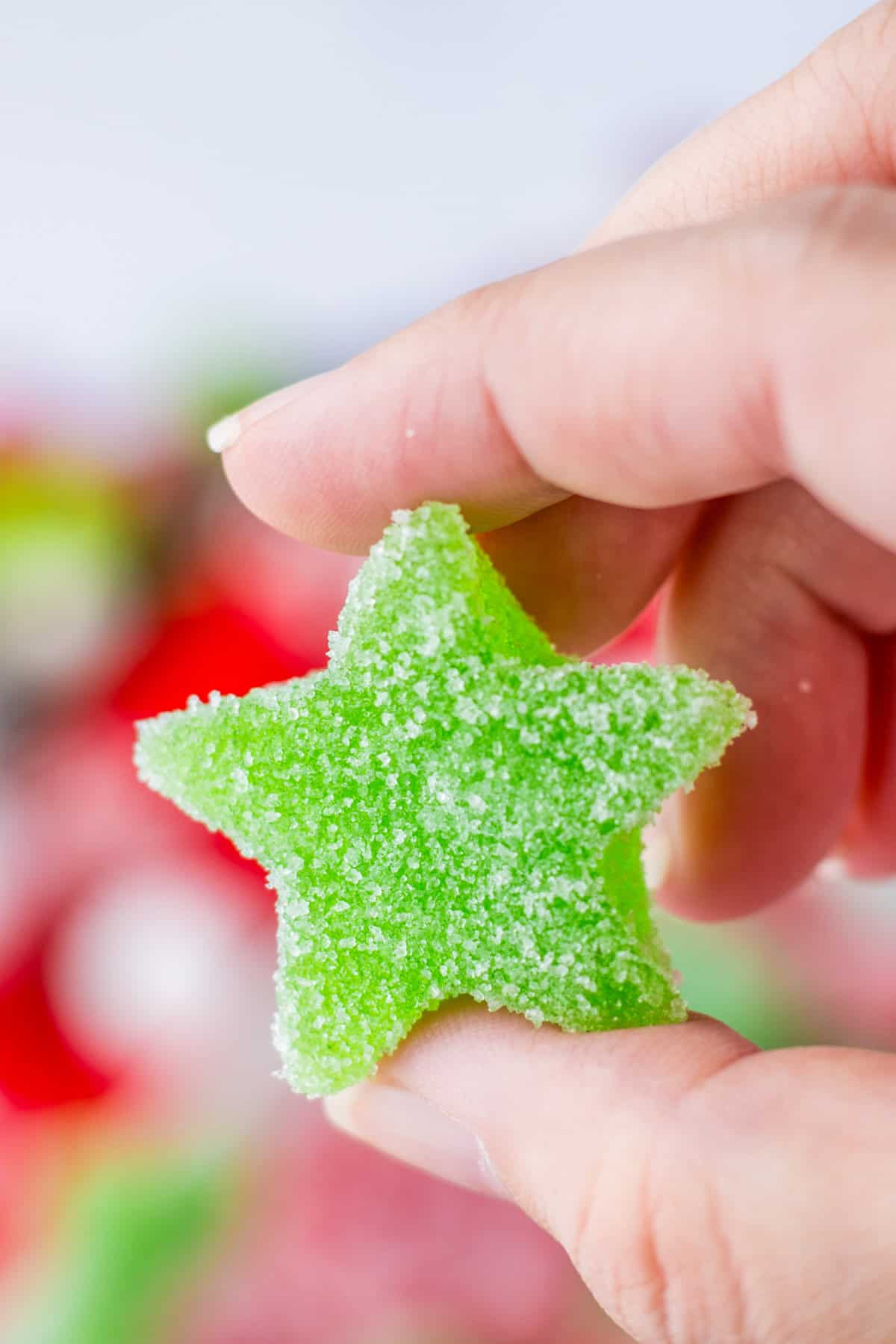 Hand holding a green star shaped gum drop candy.