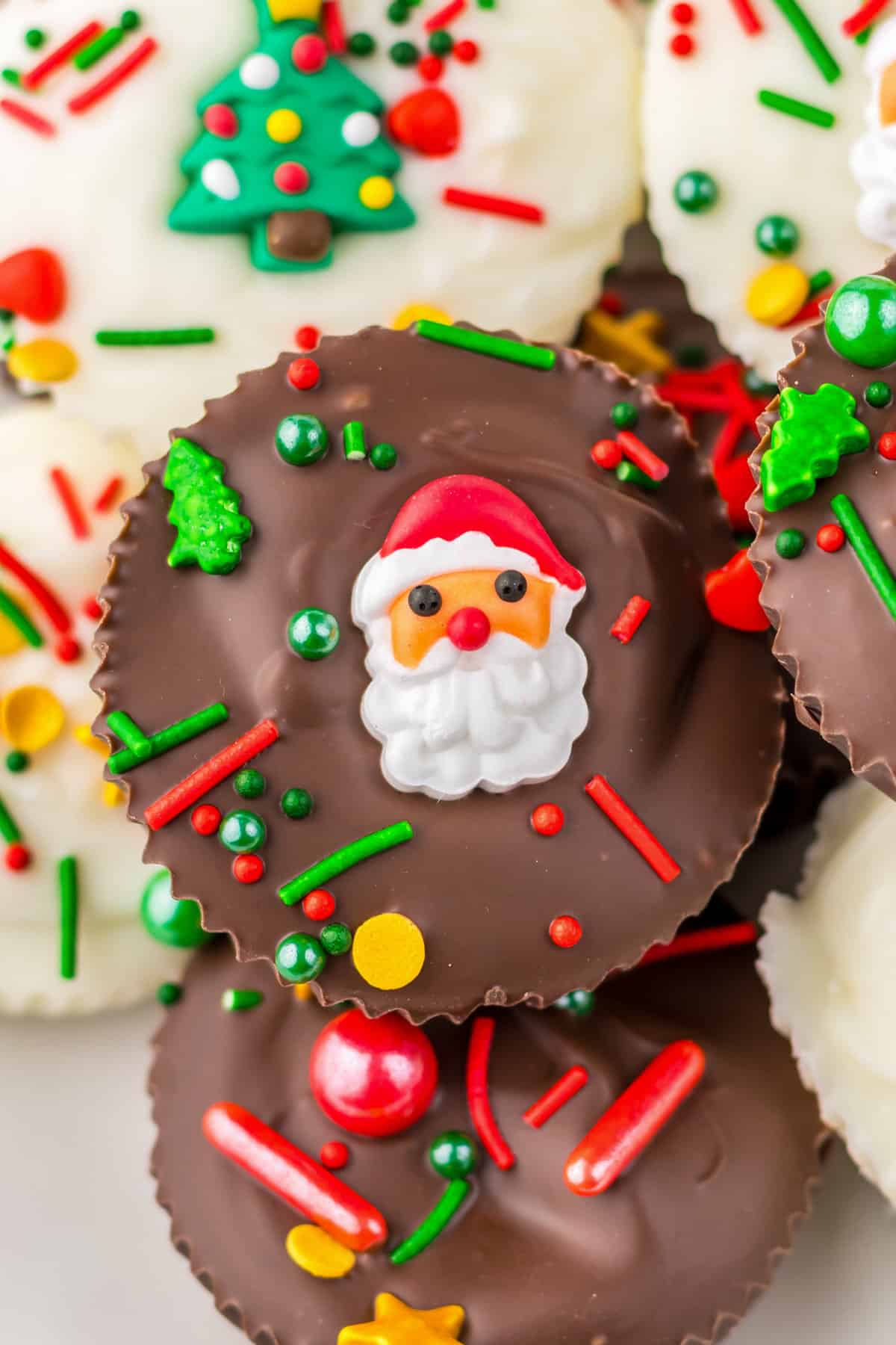 Homemade peanut butter cups decorated with christmas sprinkles and a candy santa placed in the center.