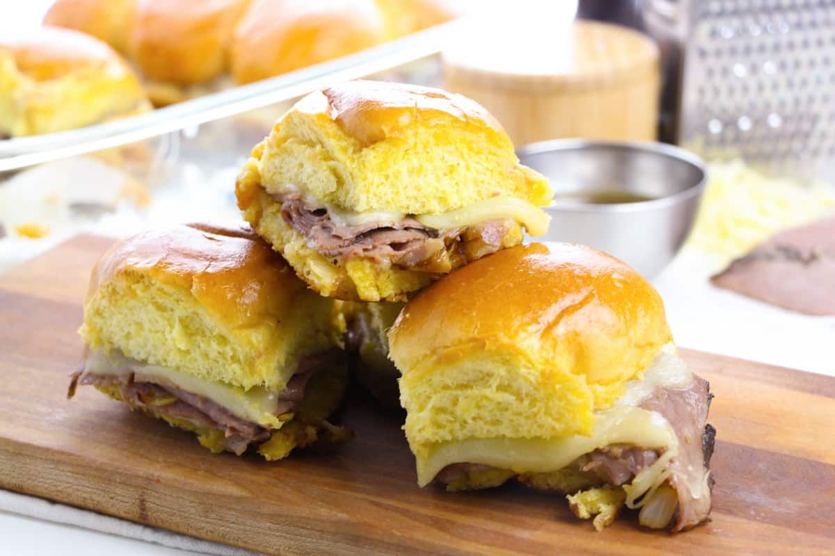 French Dip Roast Beef Sliders served on a wooden cutting board.