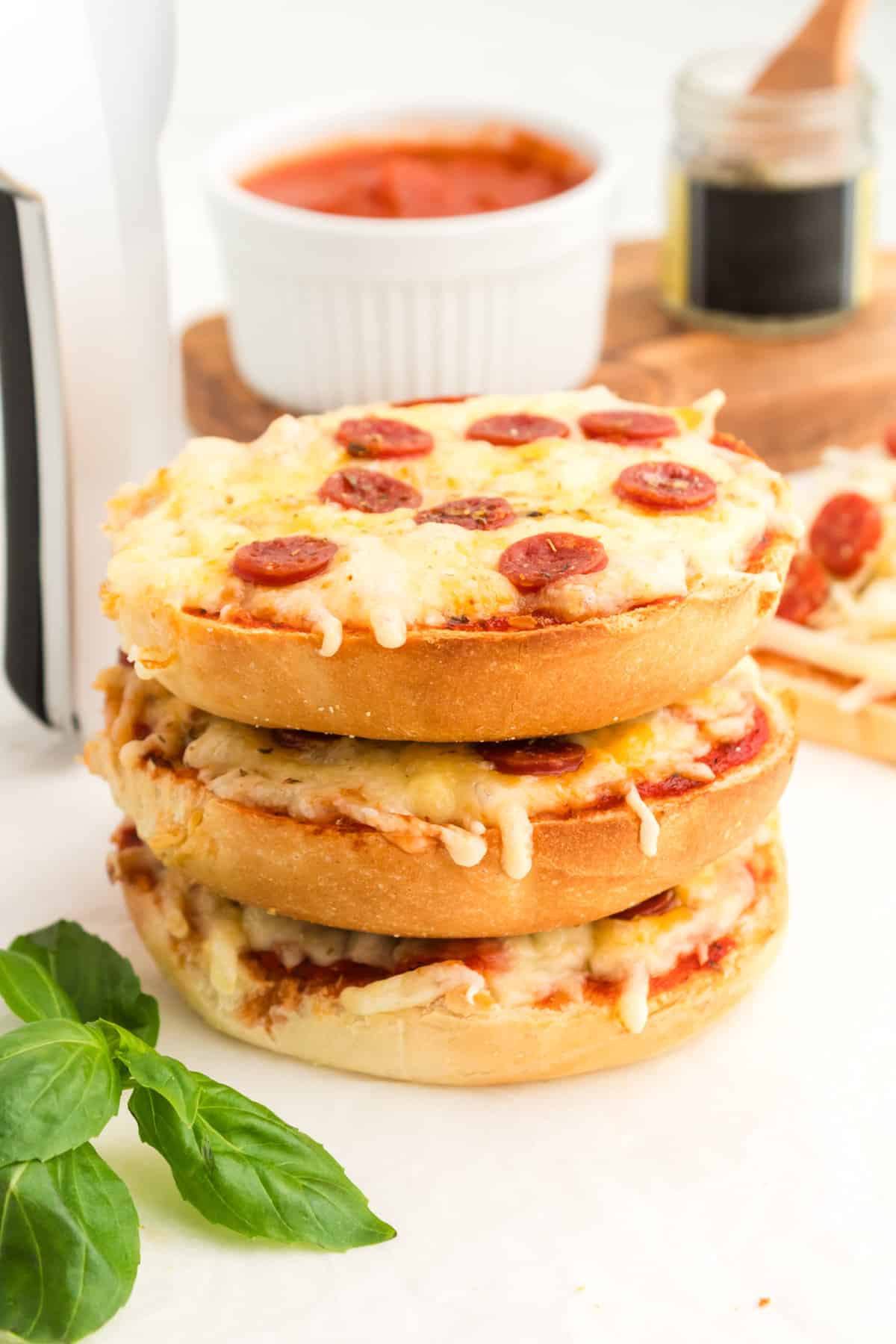 Three homemade pizza bagels with pepperoni stacked on top of one another.
