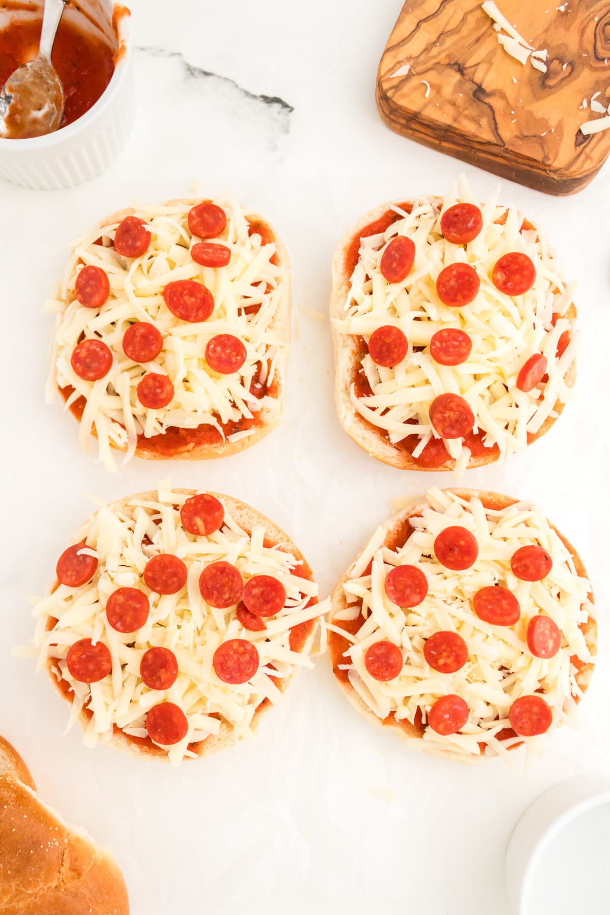 Uncooked bagel pizzas with shredded cheese and mini pepperonis.