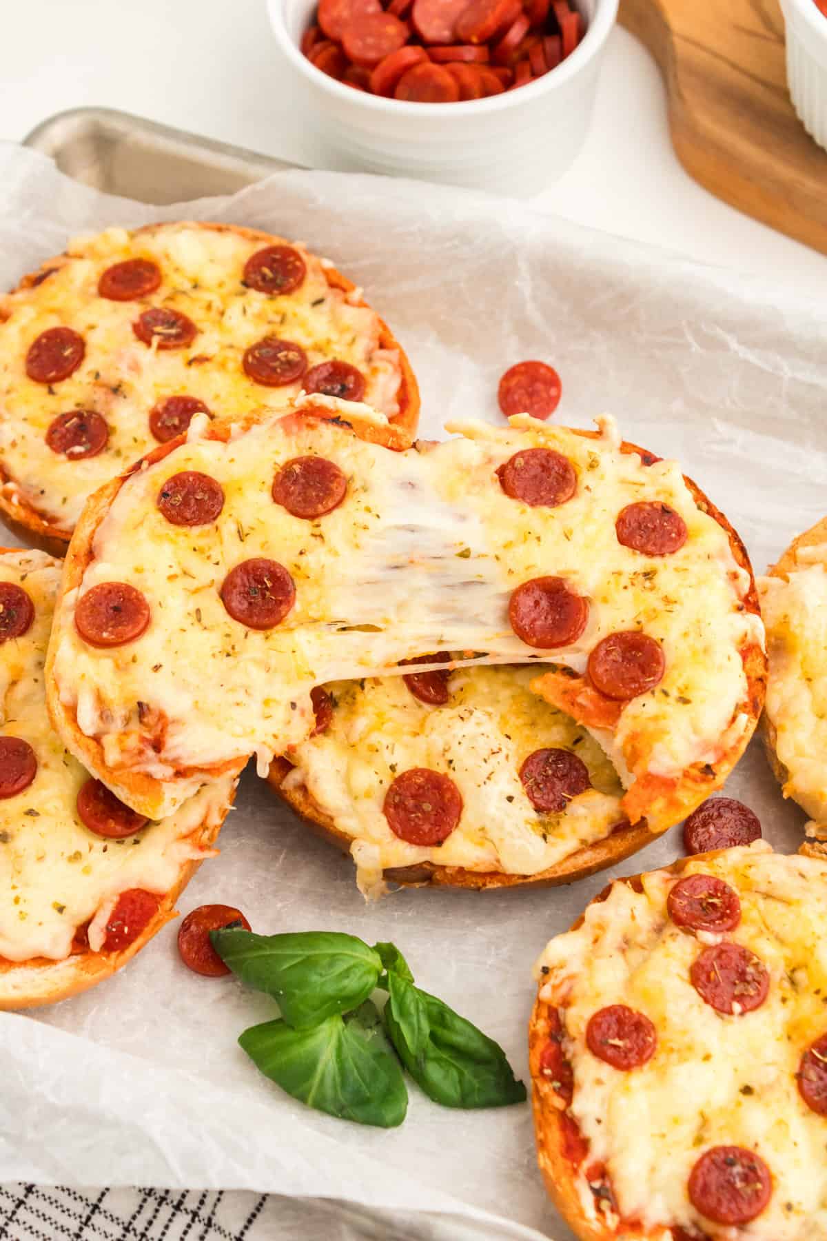 Pizza bagel torn in half to show melty cheese pull.