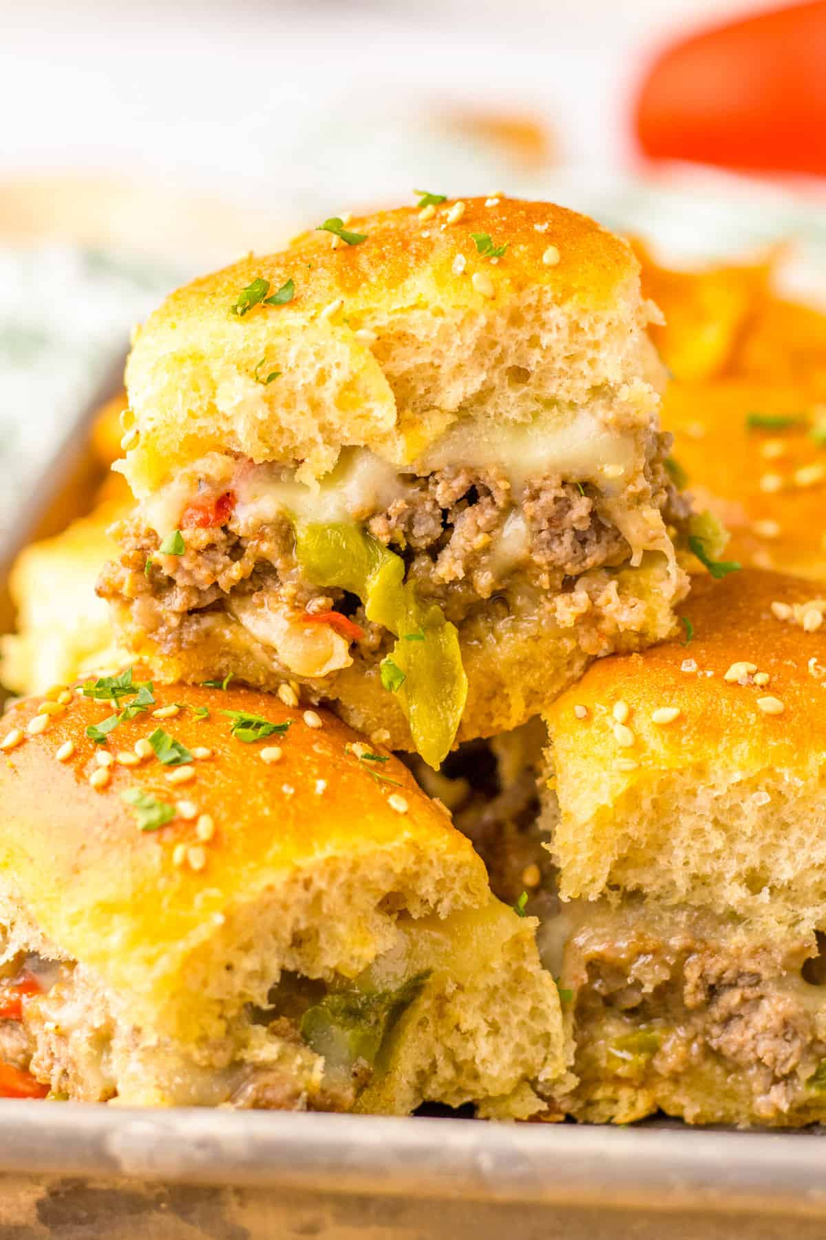 Philly Cheesesteak Sliders with Ground Beef, peppers, onions, and provolone cheese on Hawaiian Rolls.