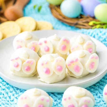 Bunny oreo balls decorated with feet and tails to look like bunny butts. Lemon oreo cookies and easter eggs are in the background.