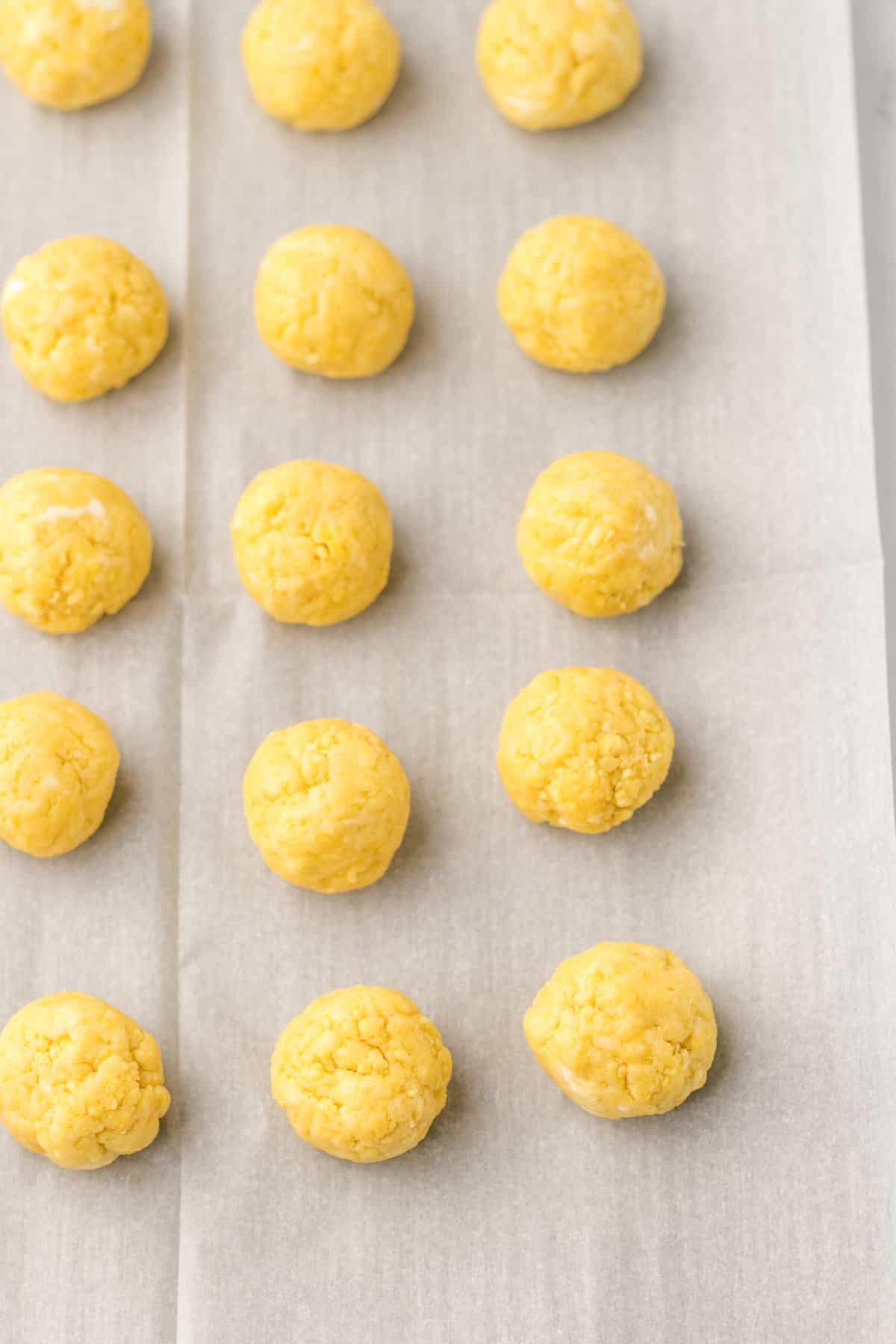 Lemon oreo cookie balls on lined sheet pan.