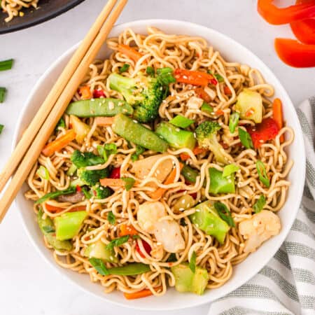 Ramen stir fry with vegetables served in a large bowl with chop sticks.