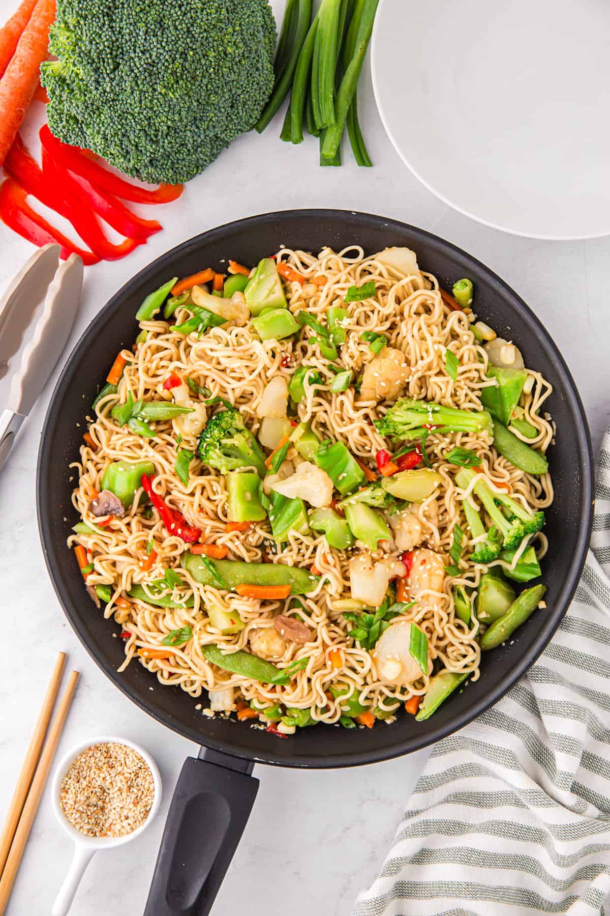 Stir fry with ramen noodles and vegetables in black pan.