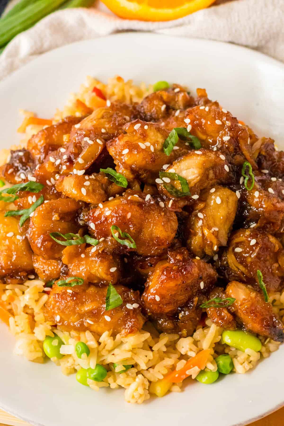 Slow Cooker Orange Chicken over fried rice on a white plate.