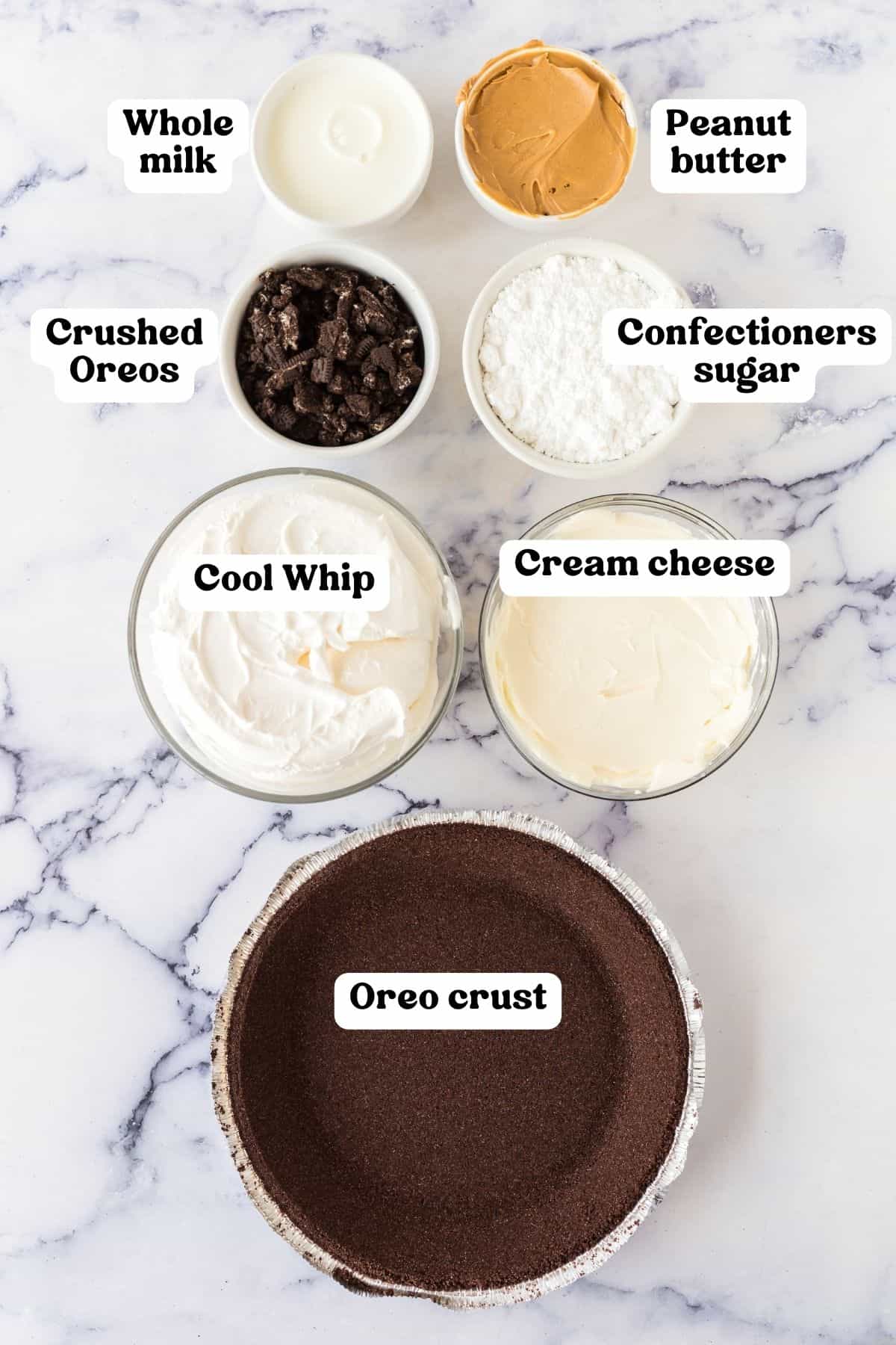 Ingredients on countertop: whole milk, creamy peanut butter, crushed oreo cookies, confectioners sugar, cool whip, cream cheese, oreo pie crust.