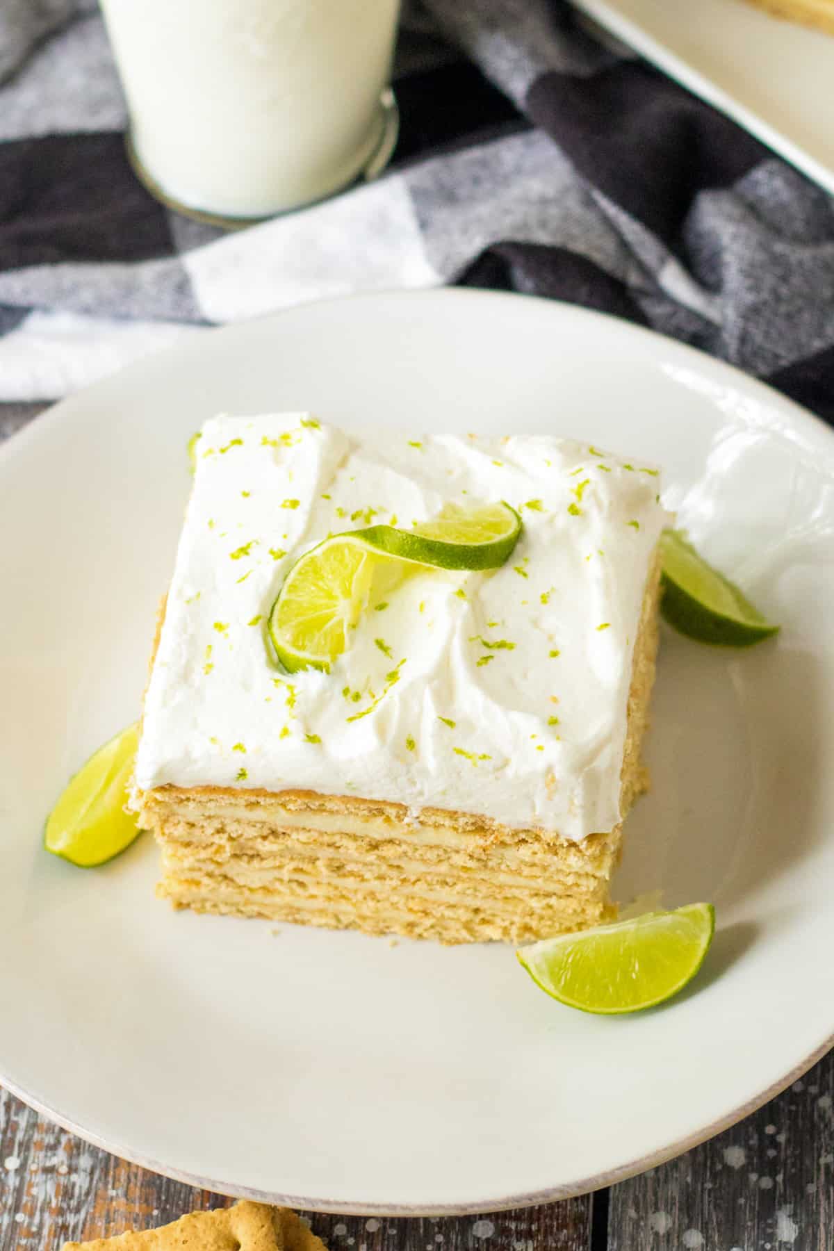 Square piece of key lime no bake cake topped with whipped cream and key lime garnish.