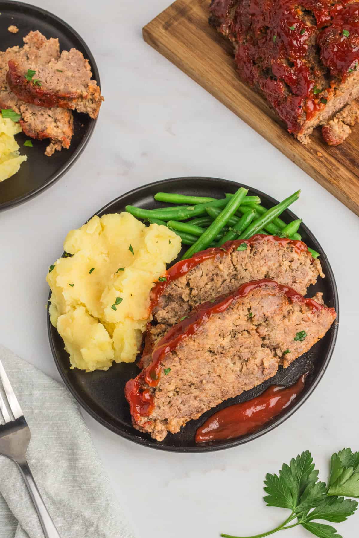 Plate with 2 slices of meatloaf, green beans, and mashed potatoes.