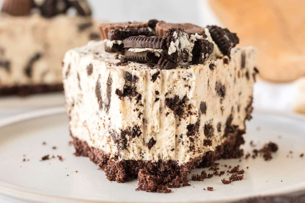 Peanut butter oreo crust pie with forkfull removed to show the creamy peanut butter filling with chunks of crushed oreo cookies.