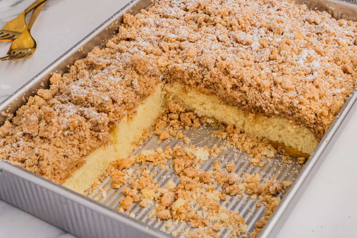 Shortcut New York style crumb cake in metal baking pan with some slices removed.