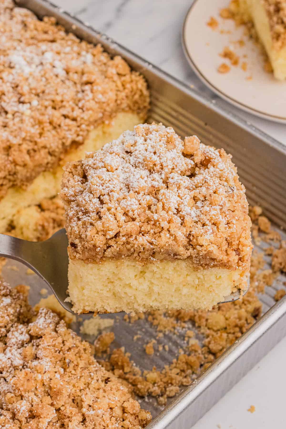 Slice of cake mix crumb cake being removed from pan with metal spatula.