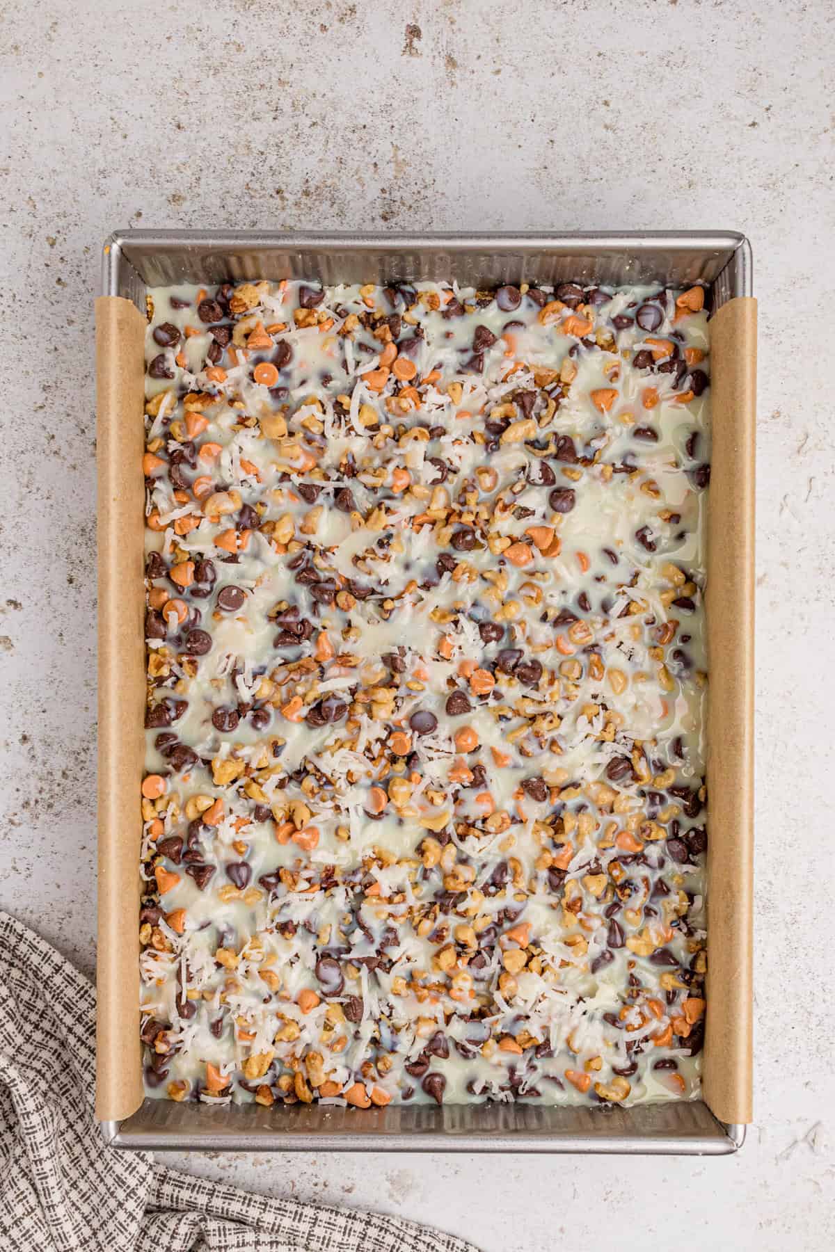 Sweetened condensed milk poured evenly over ingredients in pan.