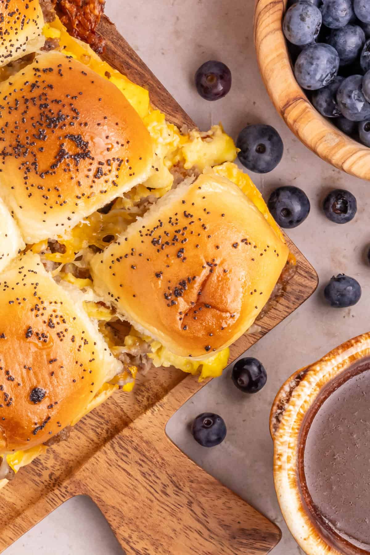 King's Hawaiian Breakfast Sliders with scrambled eggs, ground sausage, and cheese. Blueberries are served on the side.