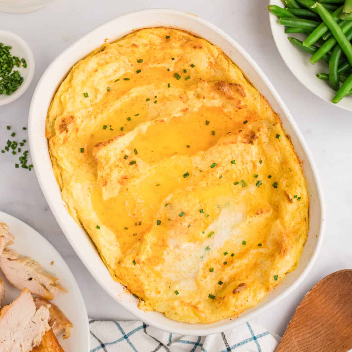 Party Potatoes with cream cheese surrounded by holiday meal including turkey, gravy, and green beans.