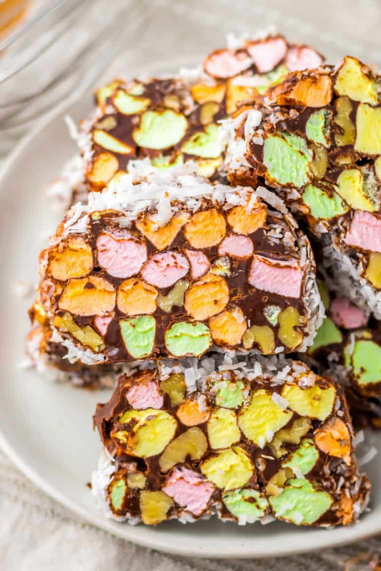 Slices of church window cookies showing vibrant pastel mini marshmallows coated in chocolate and rolled in shredded coconut. A classic no-bake treat.